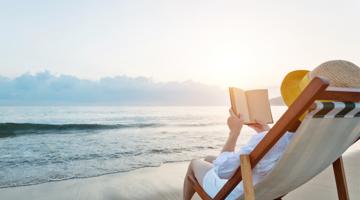A woman reading a book by the sea