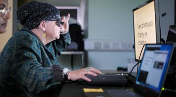 Patient being trained after eye implant surgery, looking at a computer wearing glasses