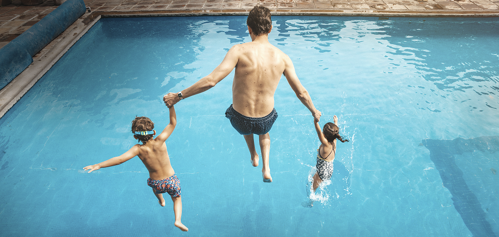 A man jumping into the swimming pool with 2 children