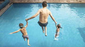 A man jumping into the swimming pool with 2 children