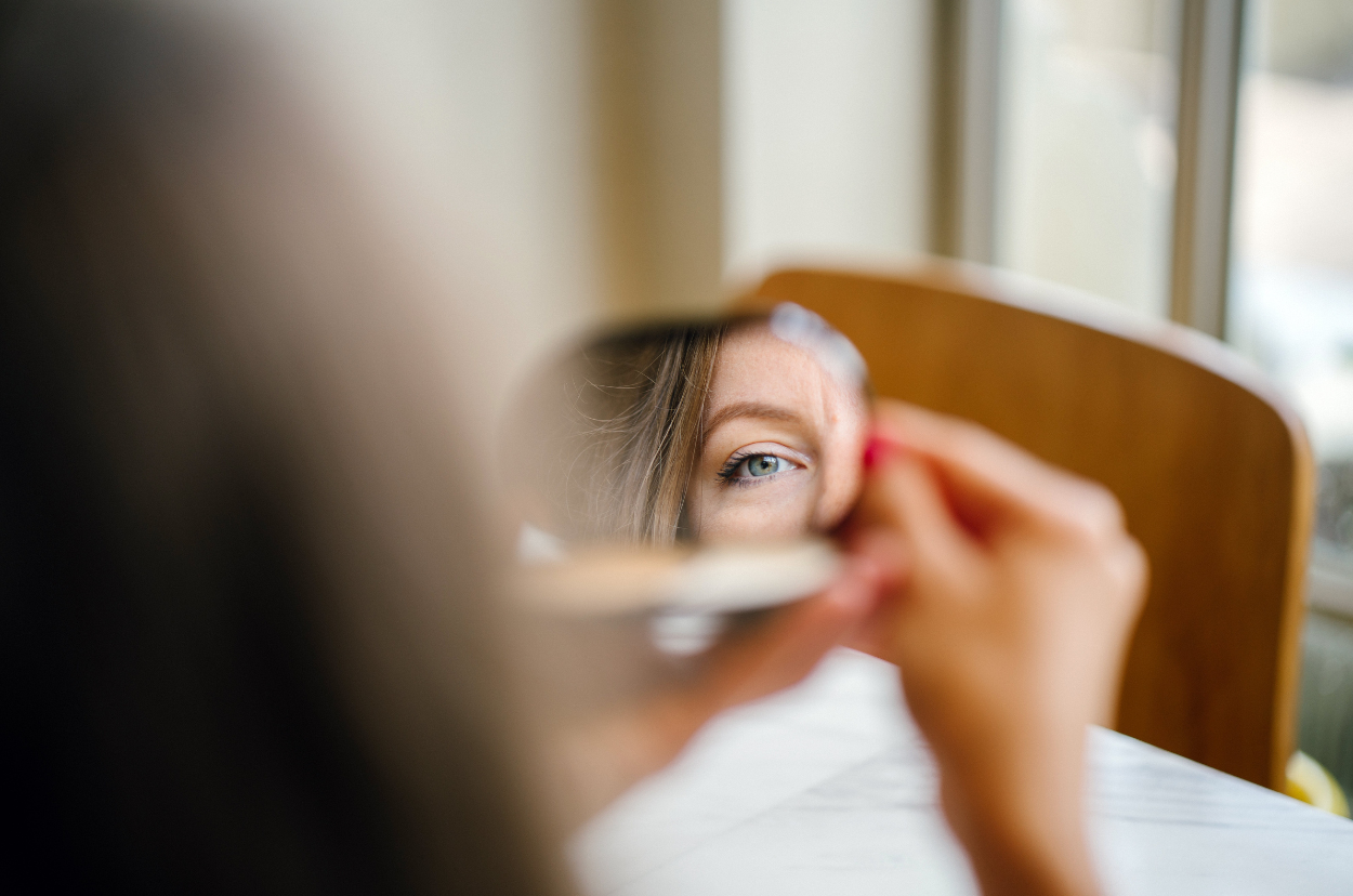 A mirror reflection of part of the woman's face and eye