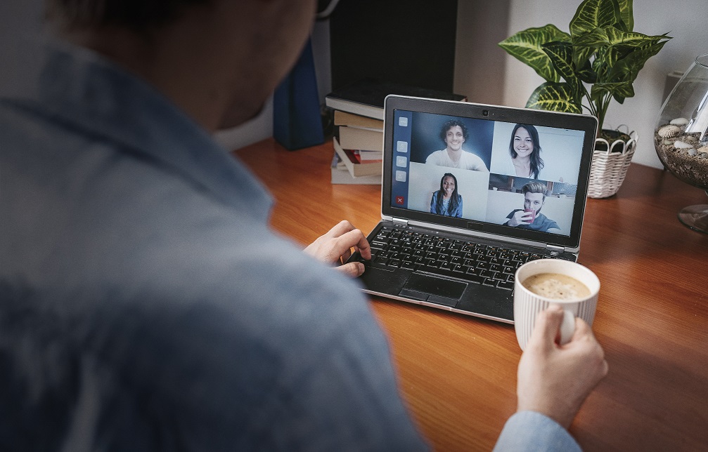 A person talking to people on his laptop and holding a cup of tea