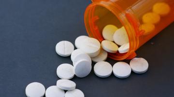 White tablets falling out of a bottle, that's laying on its side