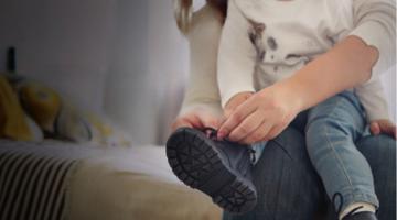 A woman holding a child and helping them with the shoelaces