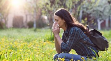 A young woman outside sneezing